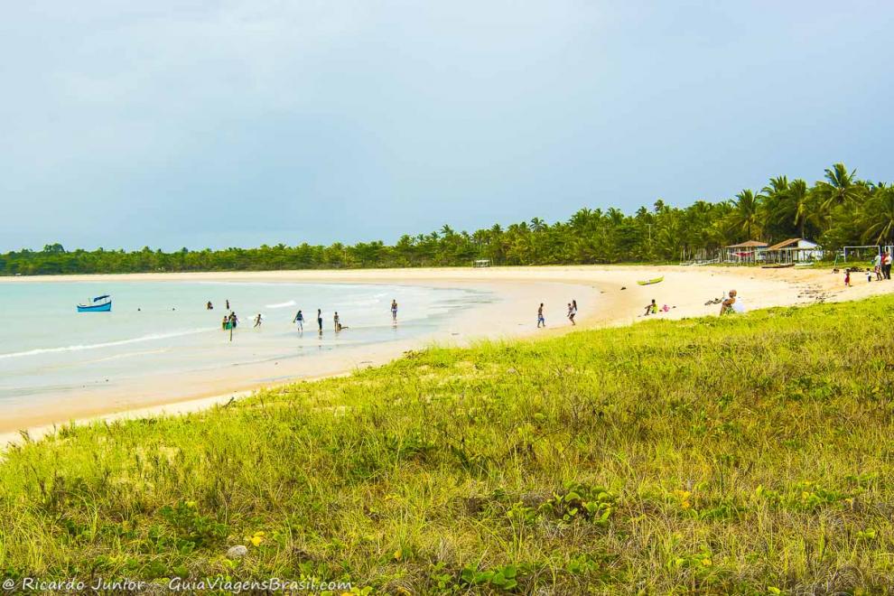 Imagem da vegetação rasteira e pessoas na Praia Cormbau.